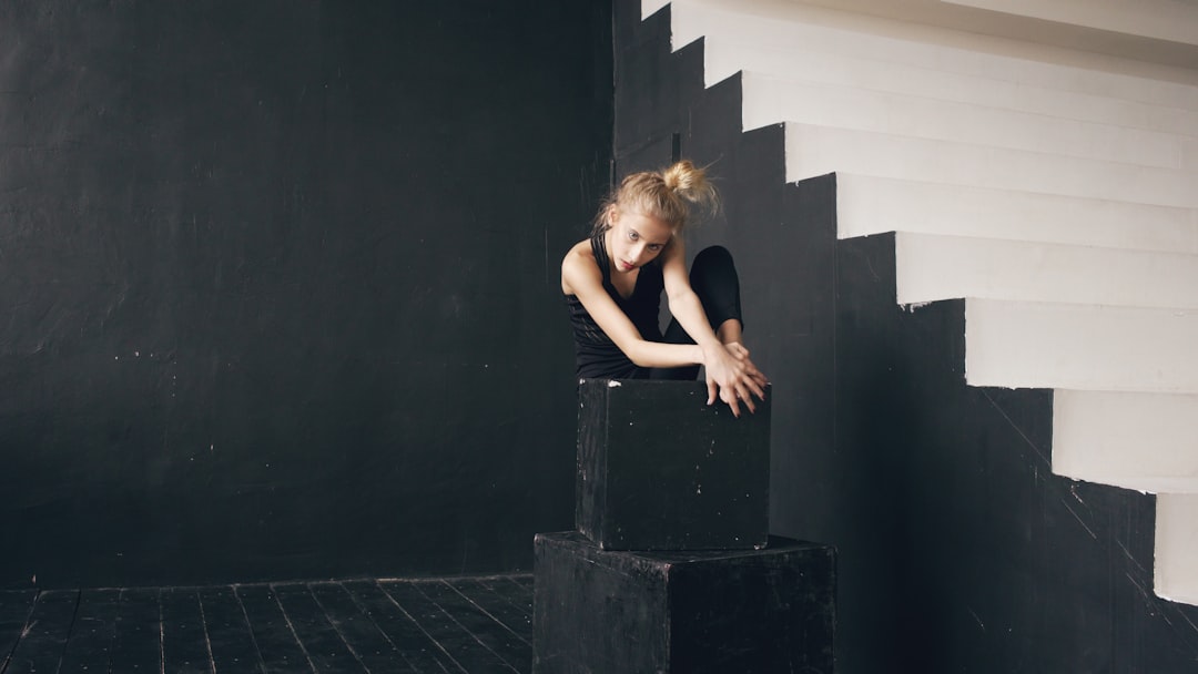 Young dancer poses on black cubes near stairs ballet dancer, emotional expression, artistic dance