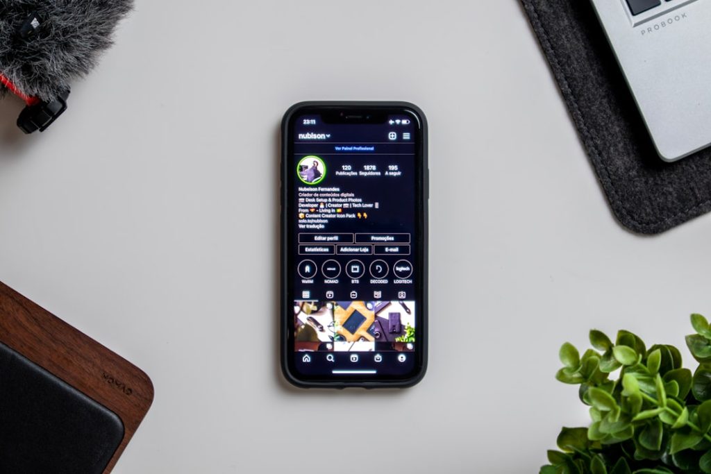 a cell phone sitting on top of a table next to a plant fantasy football app, mobile dashboard, team management