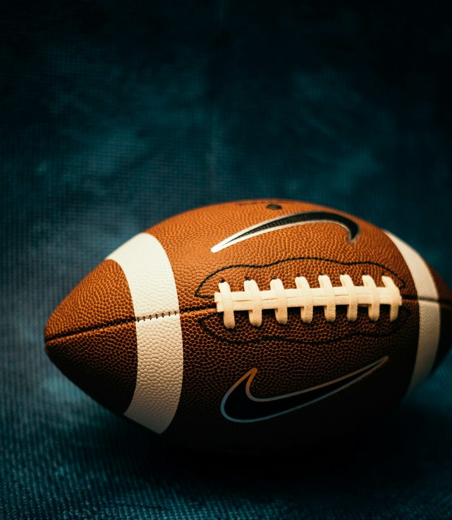 a close up of a football on a black background modern tight end, football catch, nfl stars