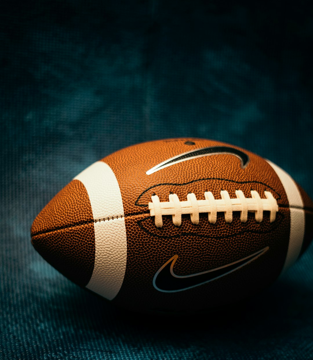 a close up of a football on a black background modern tight end, football catch, nfl stars