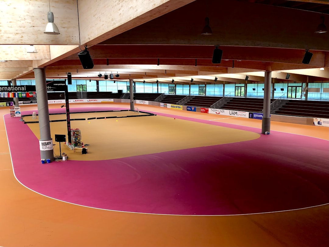 A large indoor arena with a pink floor indoor gym flooring hardwood rubber court