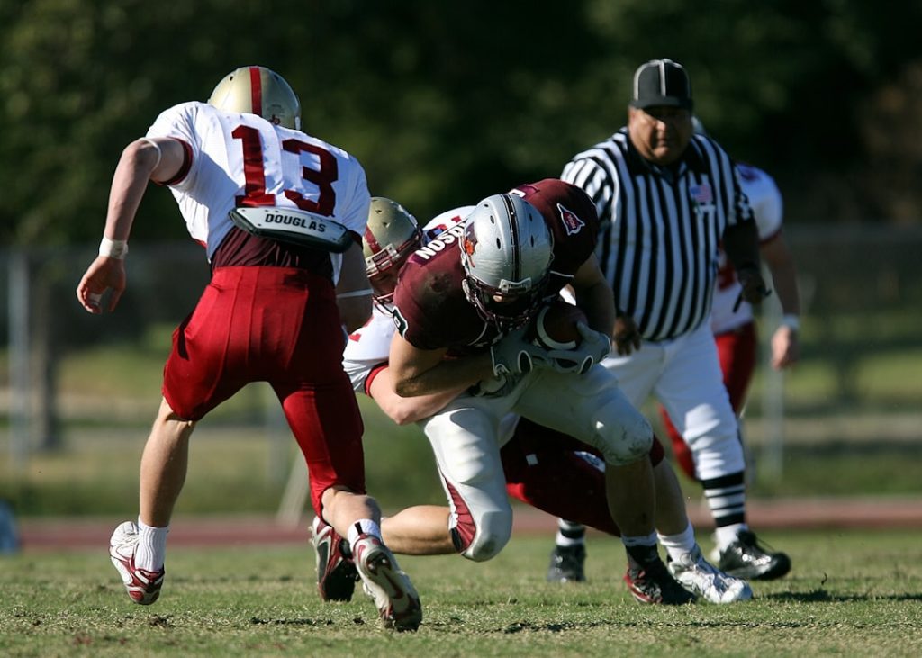 football players on green grass field linebacker stance tackle football game action