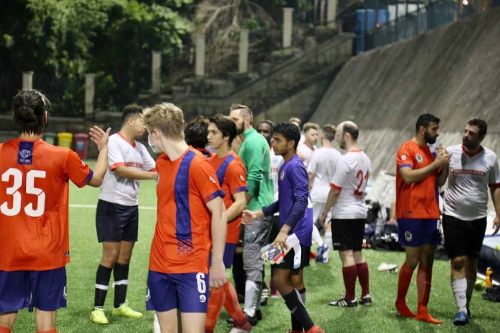 group of people in green and orange soccer jersey shirt football tactics board, formations, managers talking