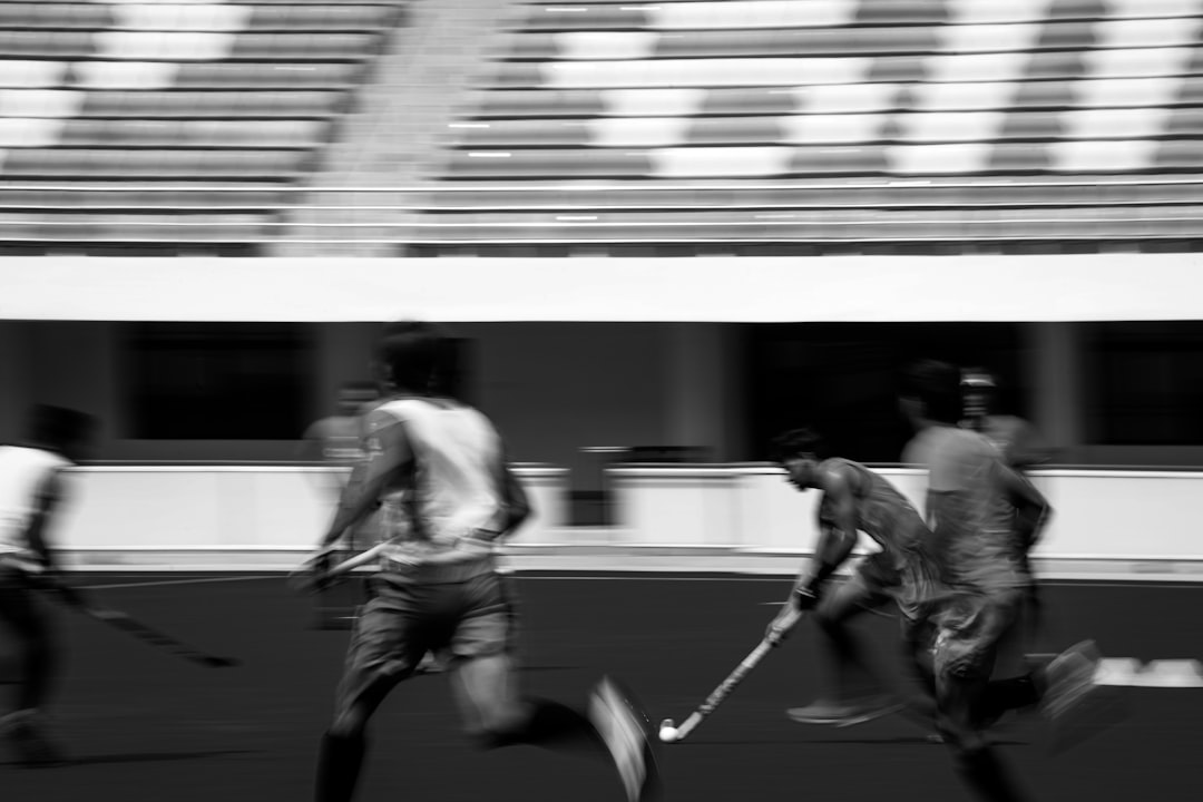 A black and white photo of a group of men playing hockey lacrosse olympics field team sport