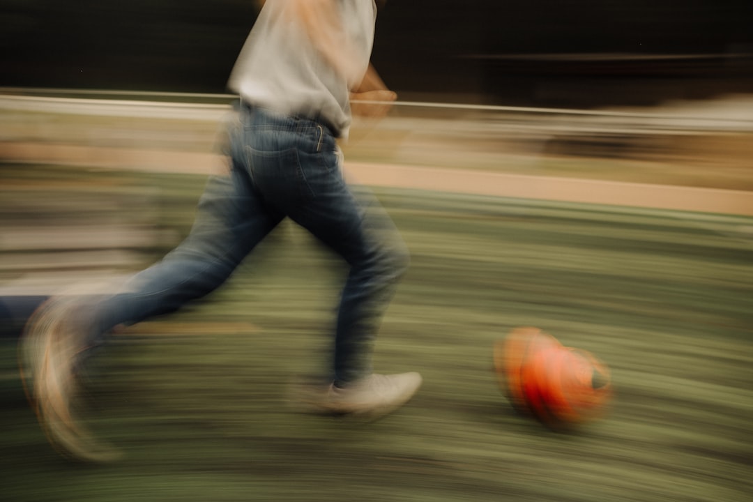 A blurry photo of a man kicking a soccer ball football spiral, ball spinning, close up throw