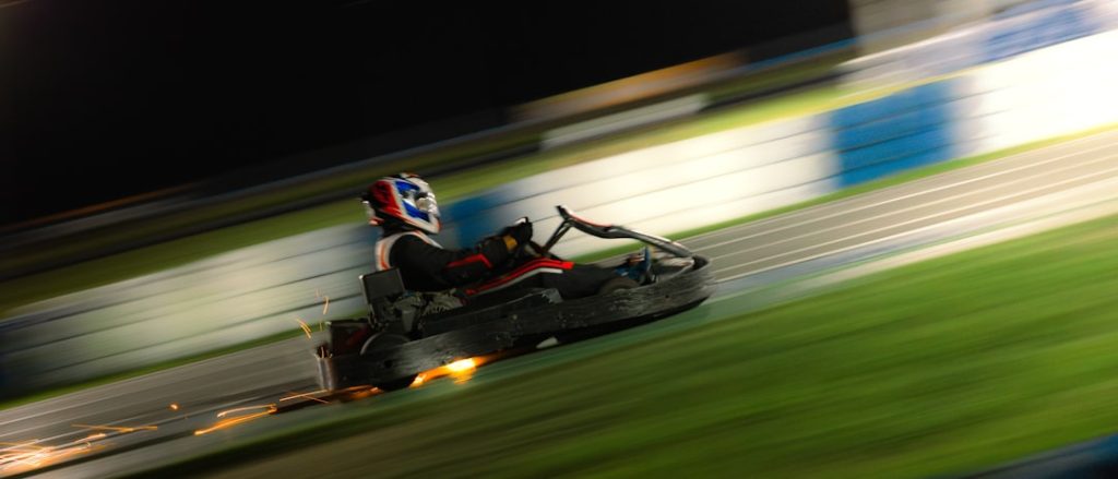 A go kart races on the track at night. indycar oval speed race, formula 1 grand prix track