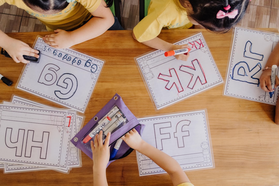 A group of children sitting at a table with paper cut outs flag football strategy playbook drawing team practice