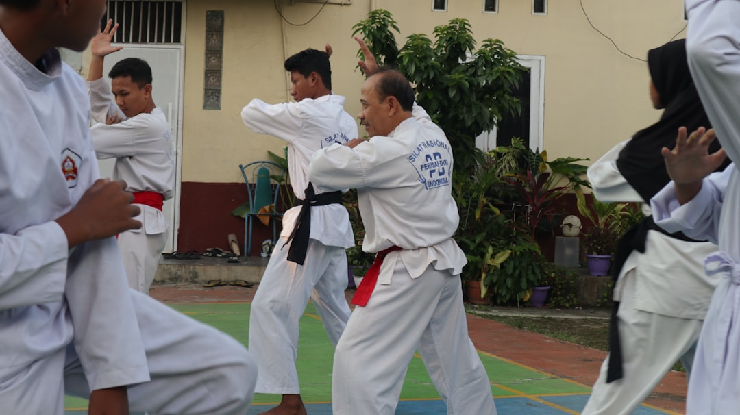 A group of men practicing karate in front of a building muay thai coach, pad work, martial arts training
