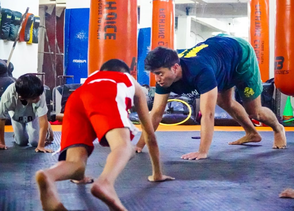 a group of men standing on top of a gym floor muay thai training, thailand gym, traditional training