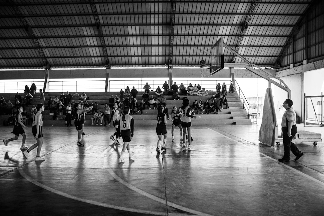 A group of people playing basketball inside of a building indoor volleyball action, players jumping, net spike