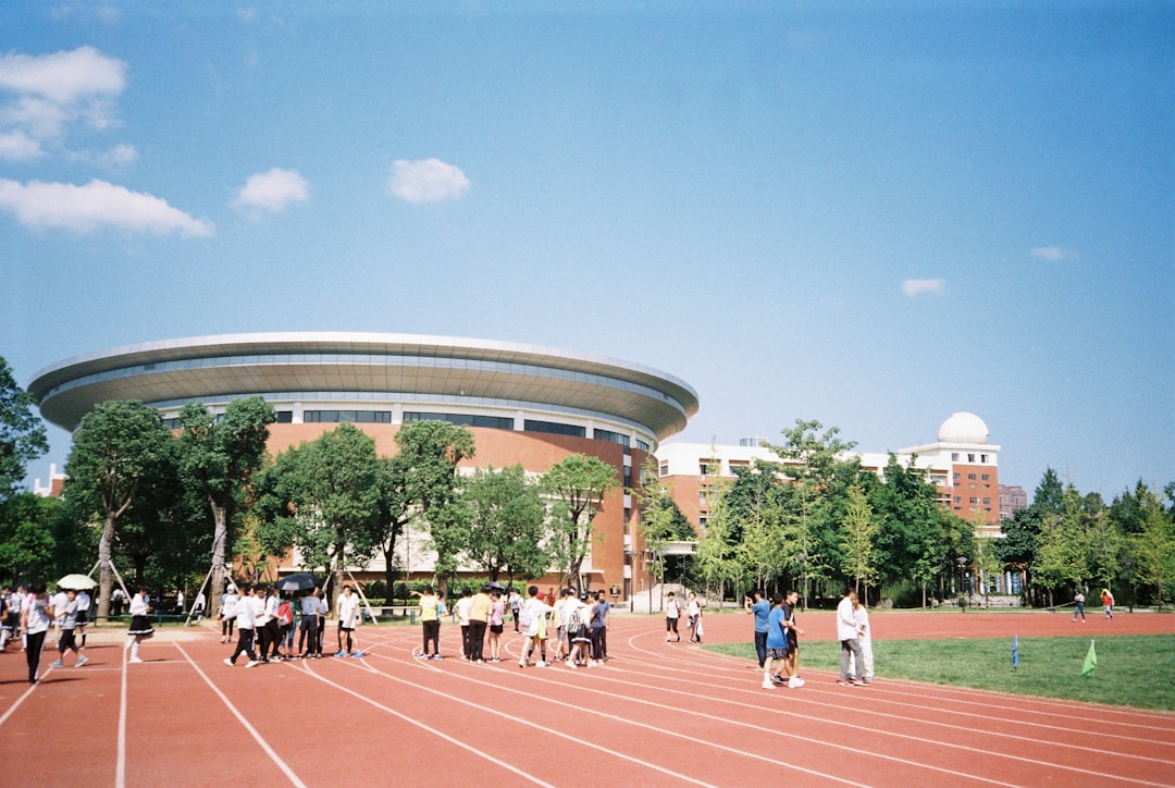 a group of people standing on a track in front of a building college lacrosse, university field, student athletes
