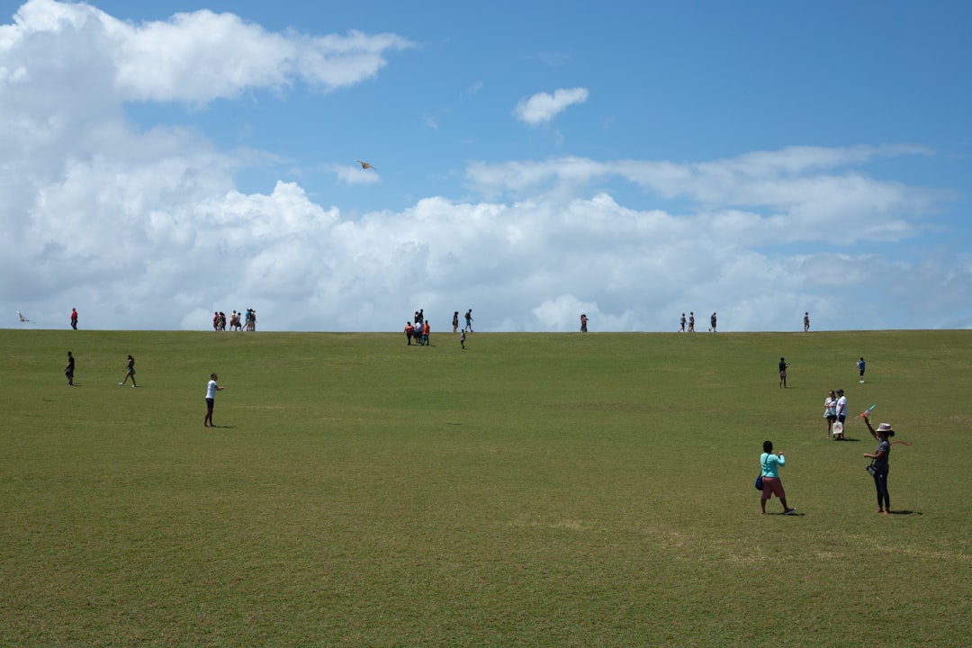 a group of people standing on top of a lush green field flag football players field action kids running