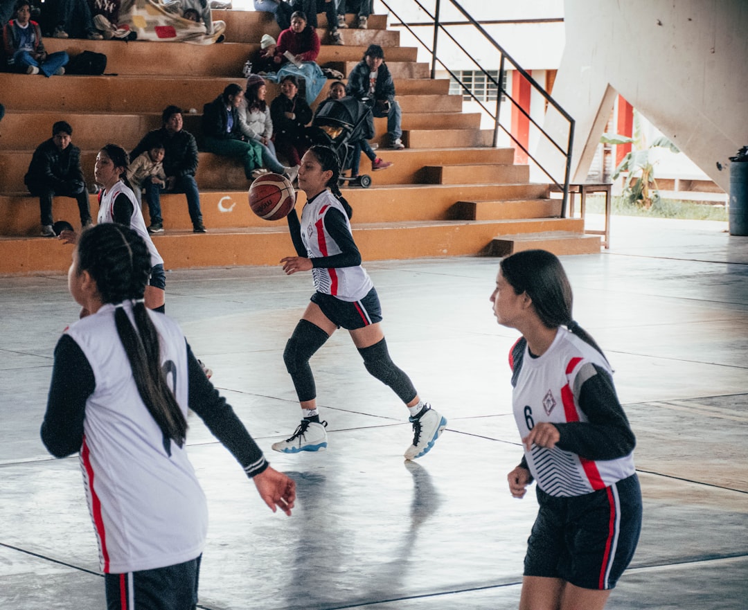 A group of young women playing a game of basketball volleyball team indoor court uniforms