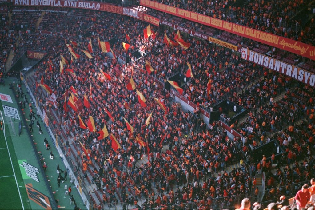 A large crowd of people at a soccer game soccer fans, intense match, stadium atmosphere, rival team flags