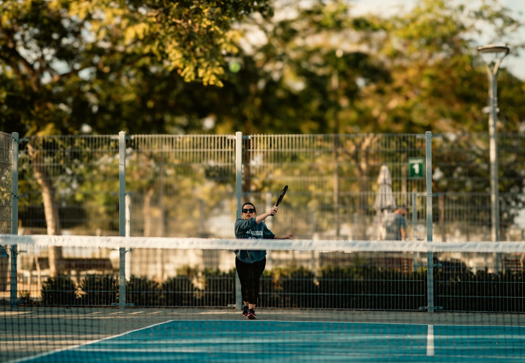 A man holding a tennis racquet on top of a tennis court youth lacrosse, practice session, soft balls