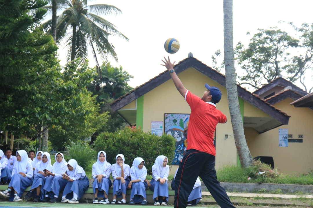 A man in a red shirt is throwing a ball youth volleyball, kids playing volleyball, junior sports