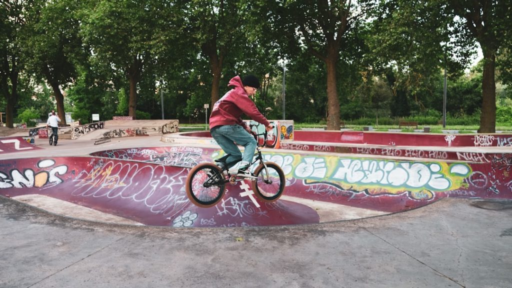 A man riding a bike up the side of a ramp bmx tricks, freestyle riding, urban setting