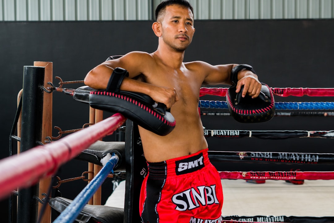 A man standing next to a boxing ring muay thai training, thailand gym, traditional training