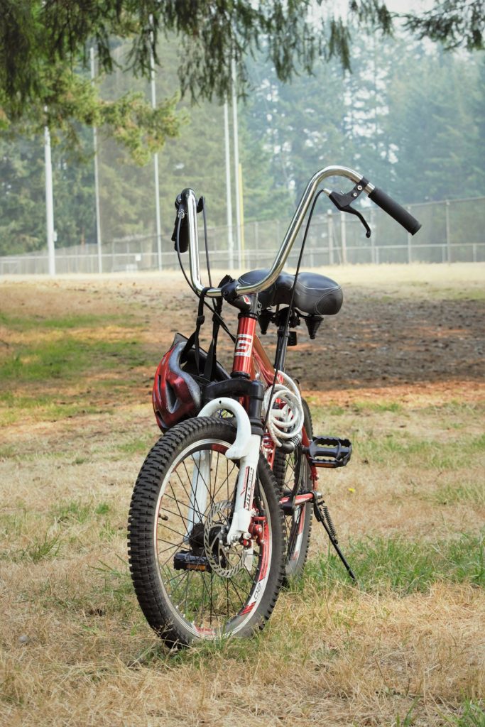 a red and white bicycle parked in a field 1980s bmx bike, vintage bmx, chrome handlebars