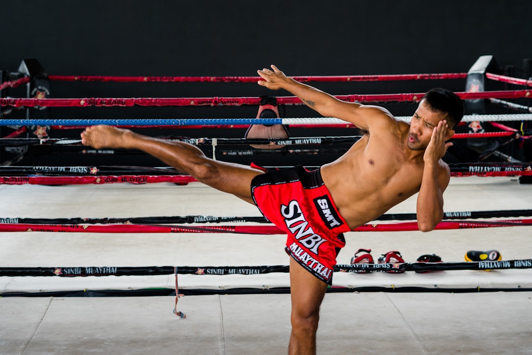 A shirtless man kicking a kick in a boxing ring muay thai fighters, traditional training, thailand gym