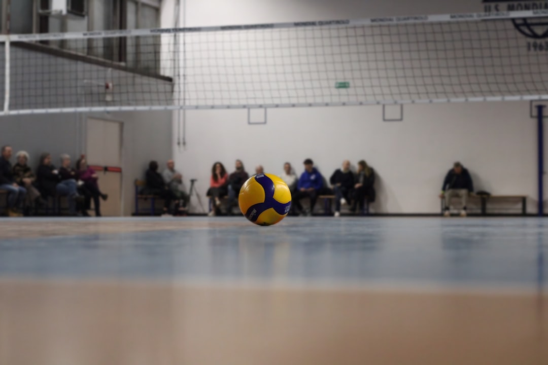 A yellow and blue ball sitting on top of a hard wood floor volleyball injury substitution bench players