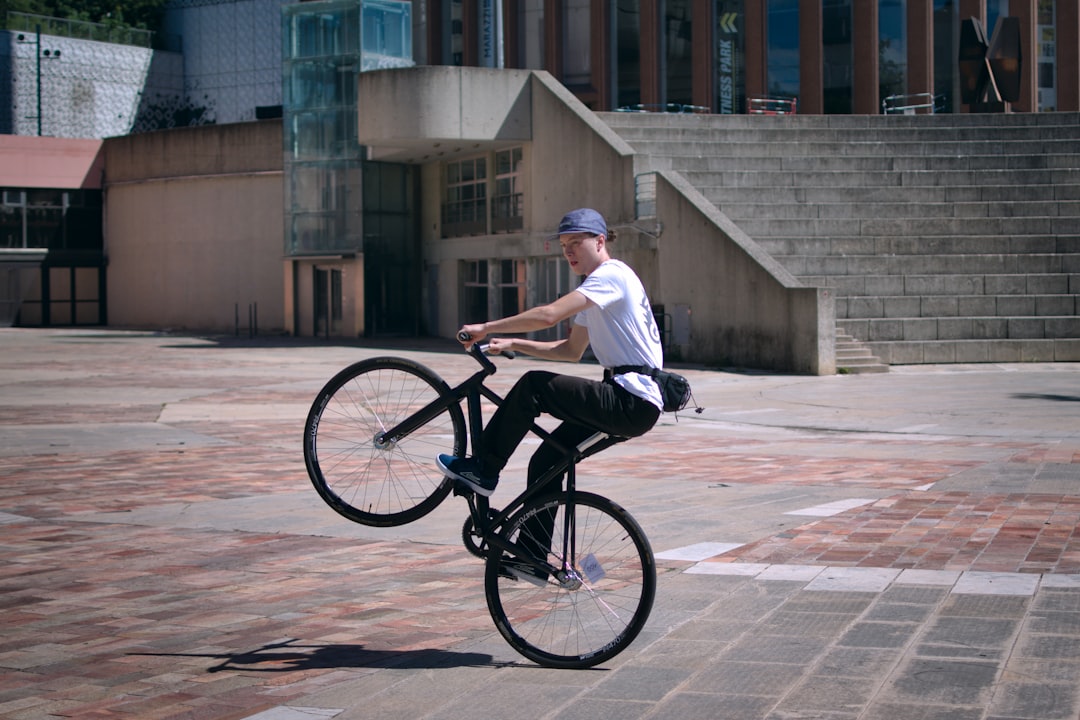 Man performing a wheelie on a bicycle outdoors bmx tricks, freestyle riding, urban setting