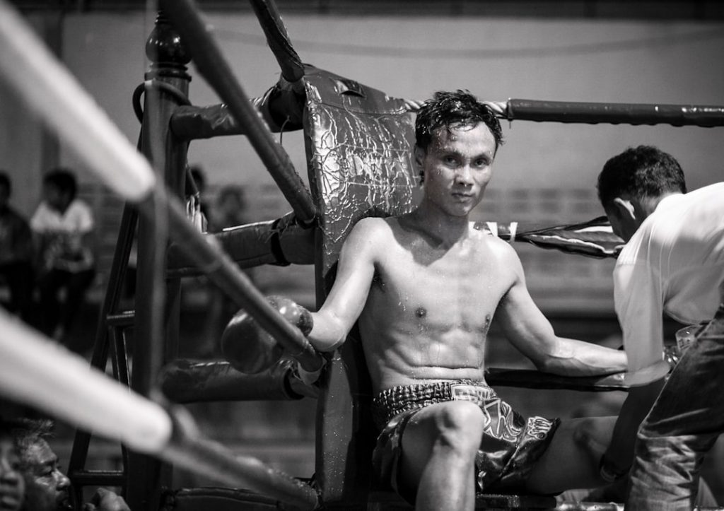 topless man in black and white shorts sitting on black metal frame muay thai fighters, traditional training, thailand gym