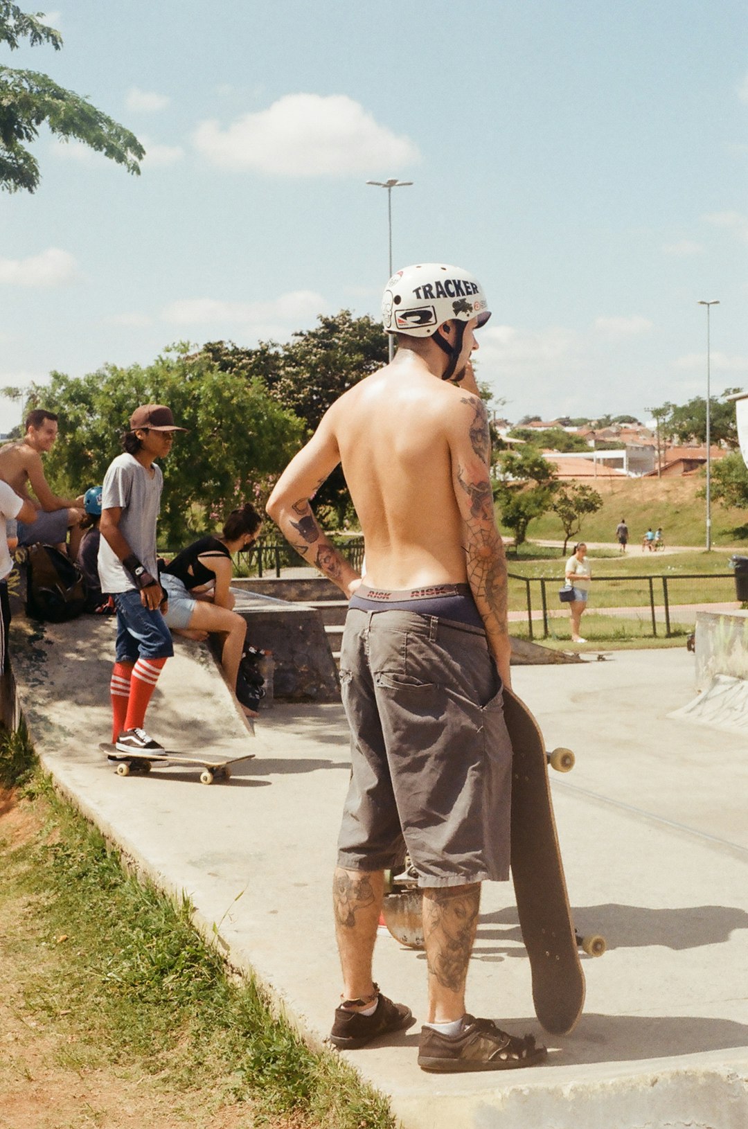 topless man in gray shorts standing on gray concrete pavement during daytime bmx rider, skateboarder, skatepark