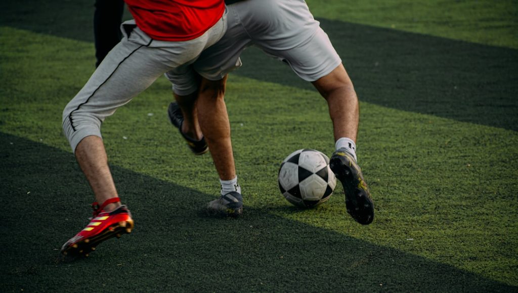 two men are playing soccer on a field football spiral, ball spinning, close up throw