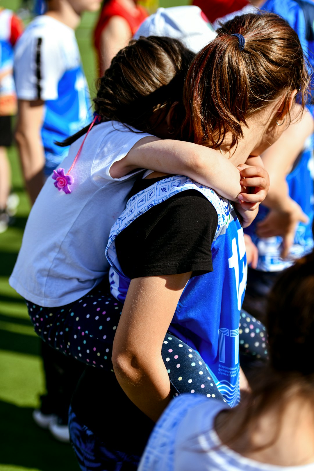 two young girls hugging each other on a field flag football kids girls competition team huddle