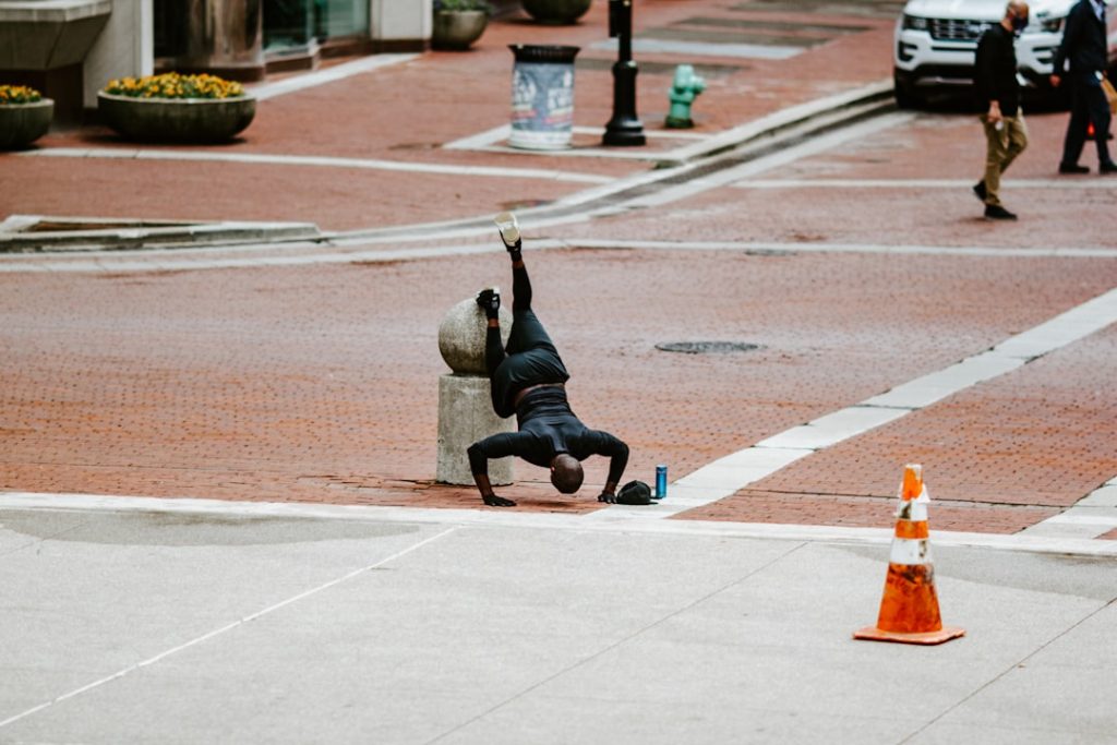 woman in black pants and gray jacket doing yoga on gray concrete floor during daytime freestyle bmx street park trick