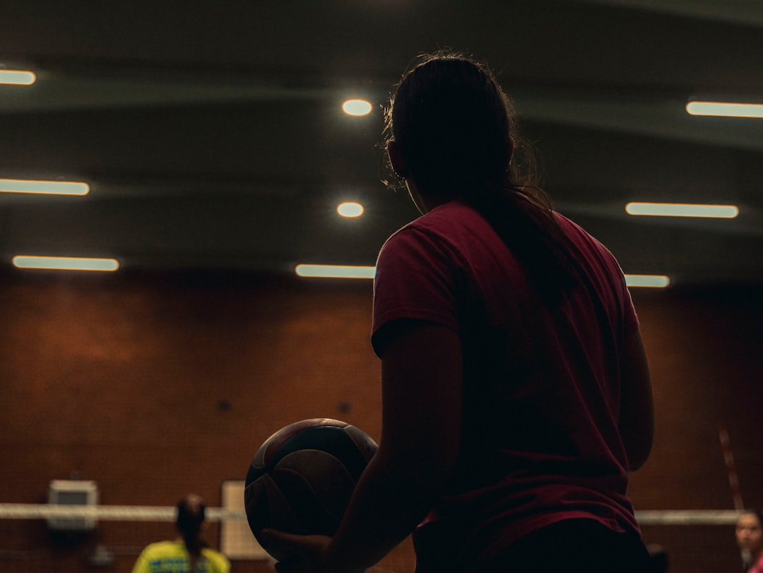 Young woman holding basketball in gymnasium. volleyball training, ankle exercise, gym workout