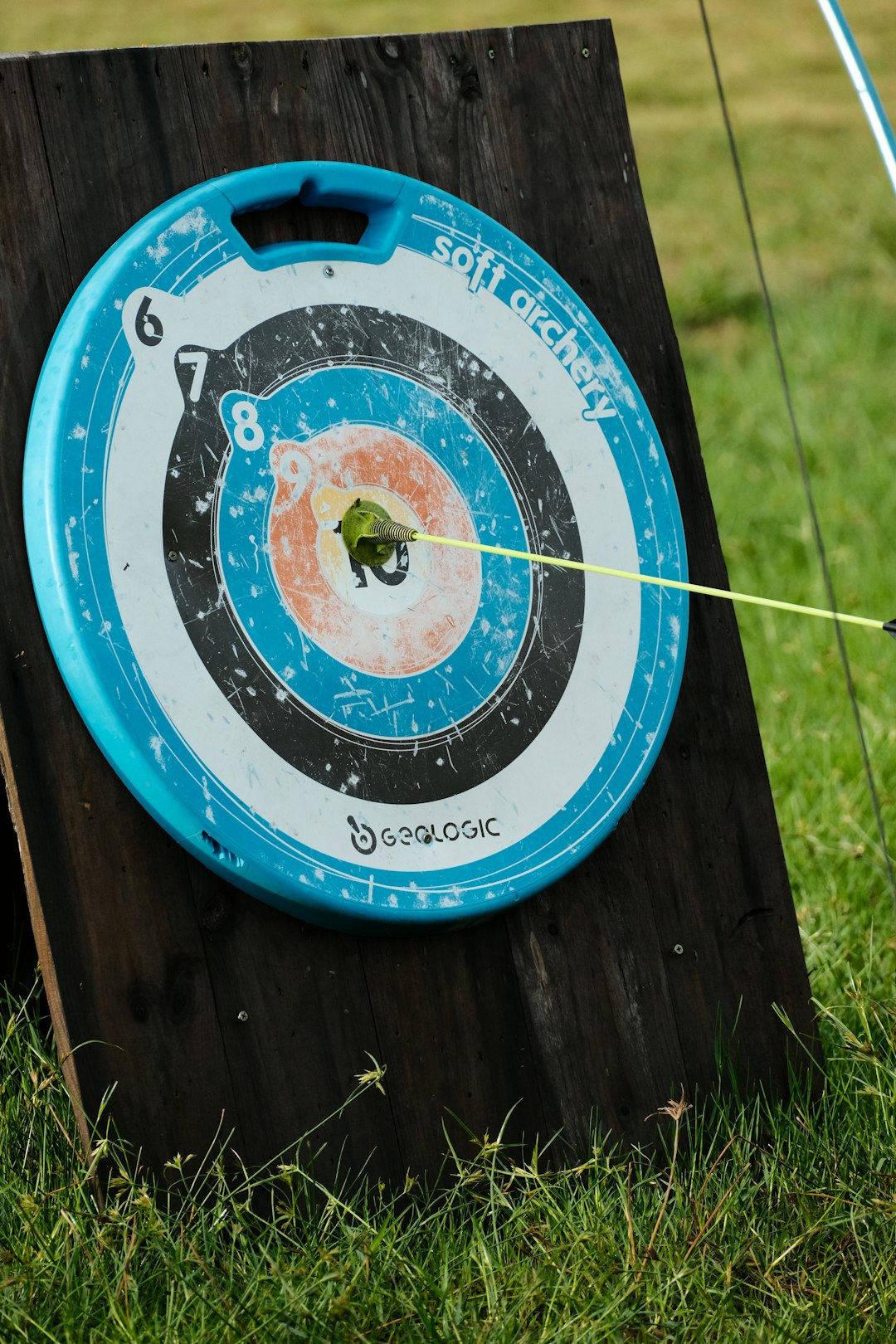 A blue and white frisbee and a black and white frisbee archery target, olympic archers, arrow hitting bullseye