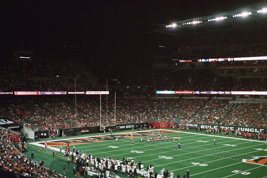 A football stadium filled with lots of people high school football fans, stadium lights, cheerleaders