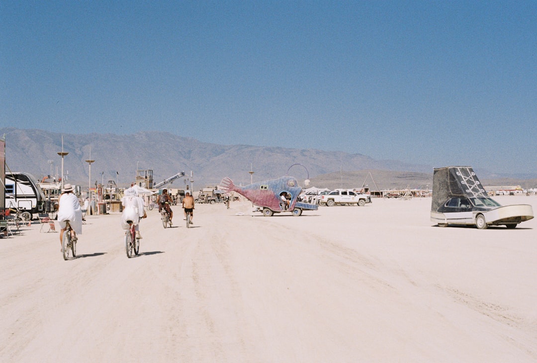 a group of people riding bikes down a dirt road cybertruck military desert offroad