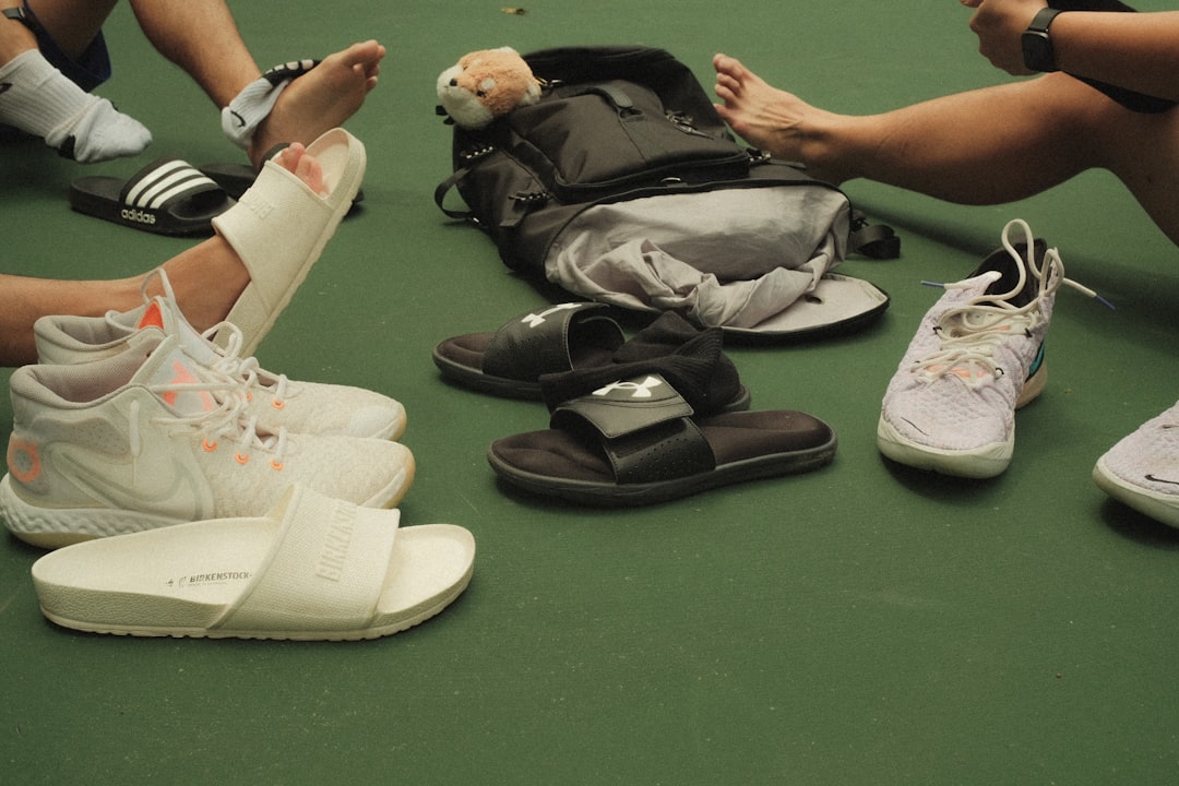 a group of people sitting on the ground with their shoes on athletes gear, ankle brace, sports bag