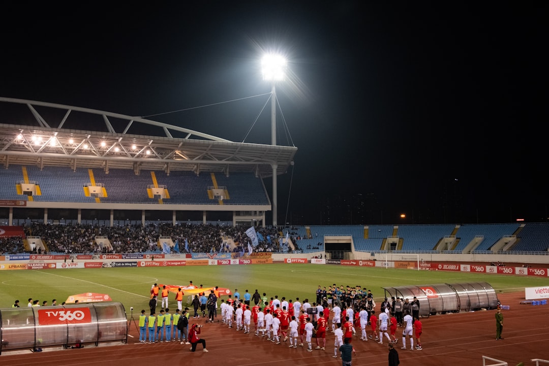 A group of people standing on top of a soccer field soccer fans, intense match, stadium atmosphere, rival team flags