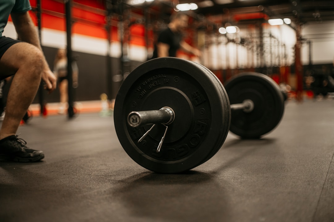 a man squatting down next to a barbell in a gym sports fan gym, tv sports, home workout