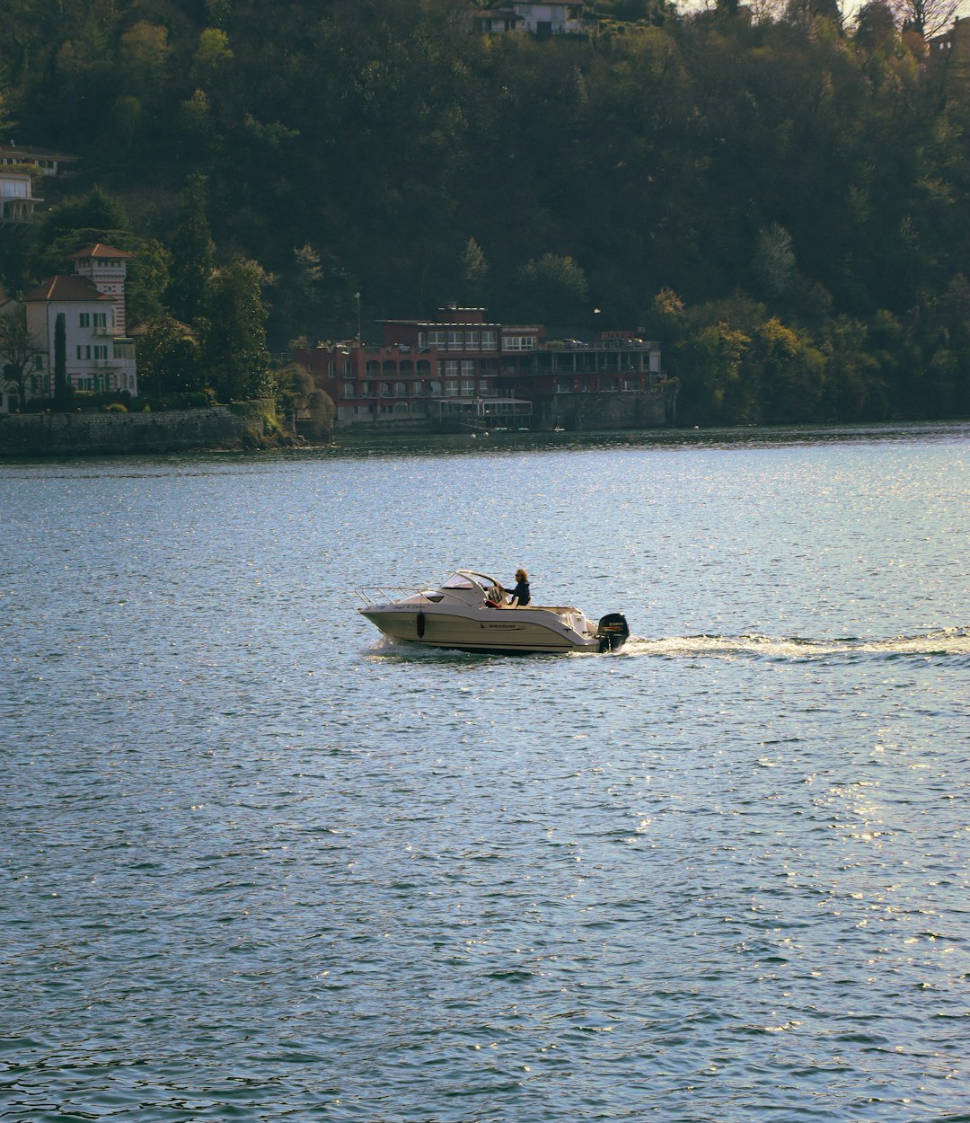 a small boat is traveling across the water calm lake water skiing safe location boat