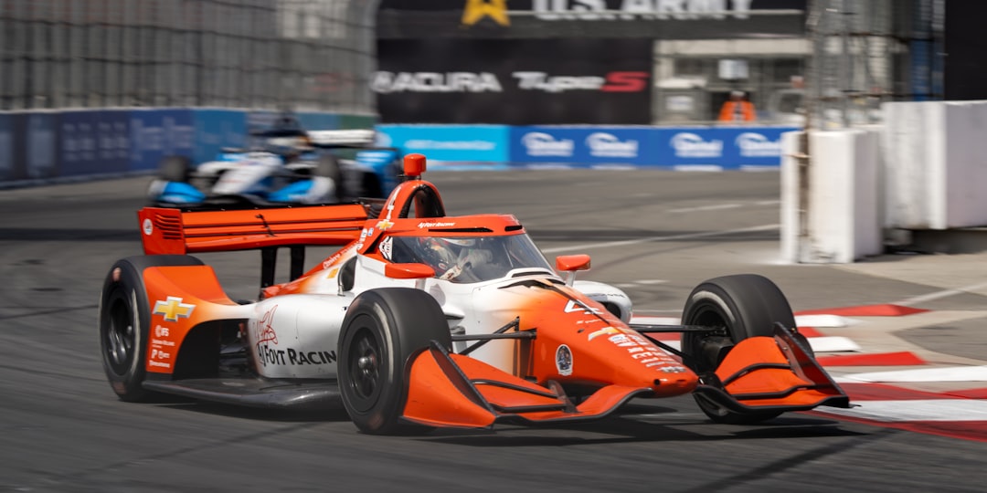 Orange and white race car speeds around corner. formula 1 car components, indycar design closeup