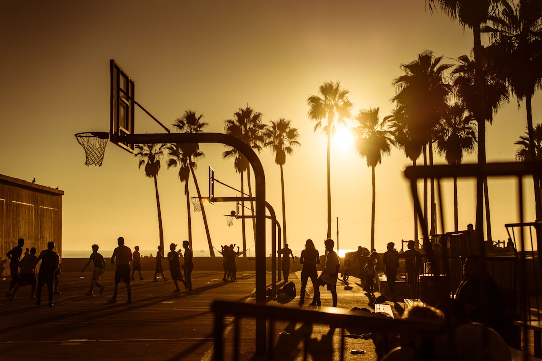 silhouette photo of people in basketball court during golden hour Los Angeles Lakers players, NBA game night, basketball court lights