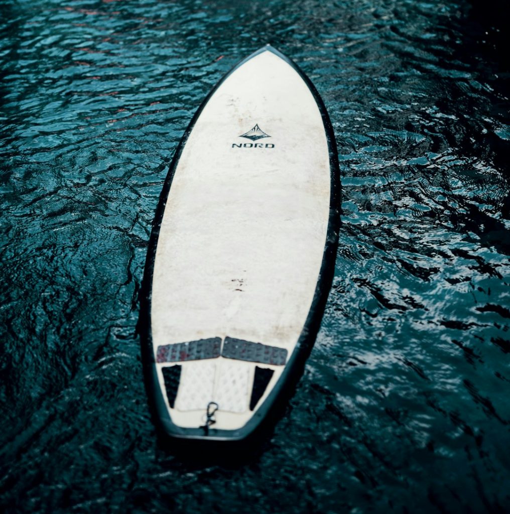 white and black surfboard on water pontoon boat, wakeboarder, water sport