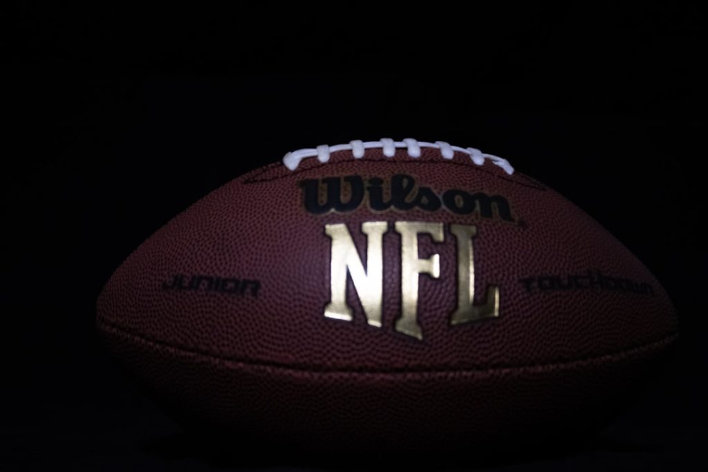 a close up of a football on a black background dolphins offense, tua pass, rams defense, nfl action