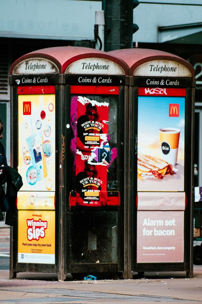 a couple of vending machines sitting on the side of a road overused ads, digital screens, marketing fatigue