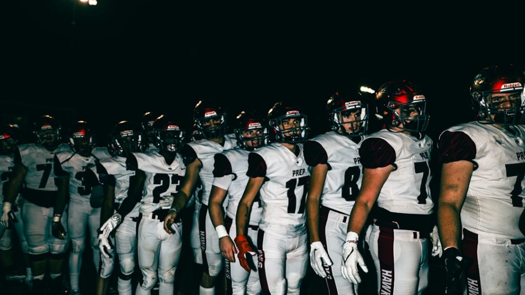 a group of football players college football stadium night game, packed stands, team uniforms close up