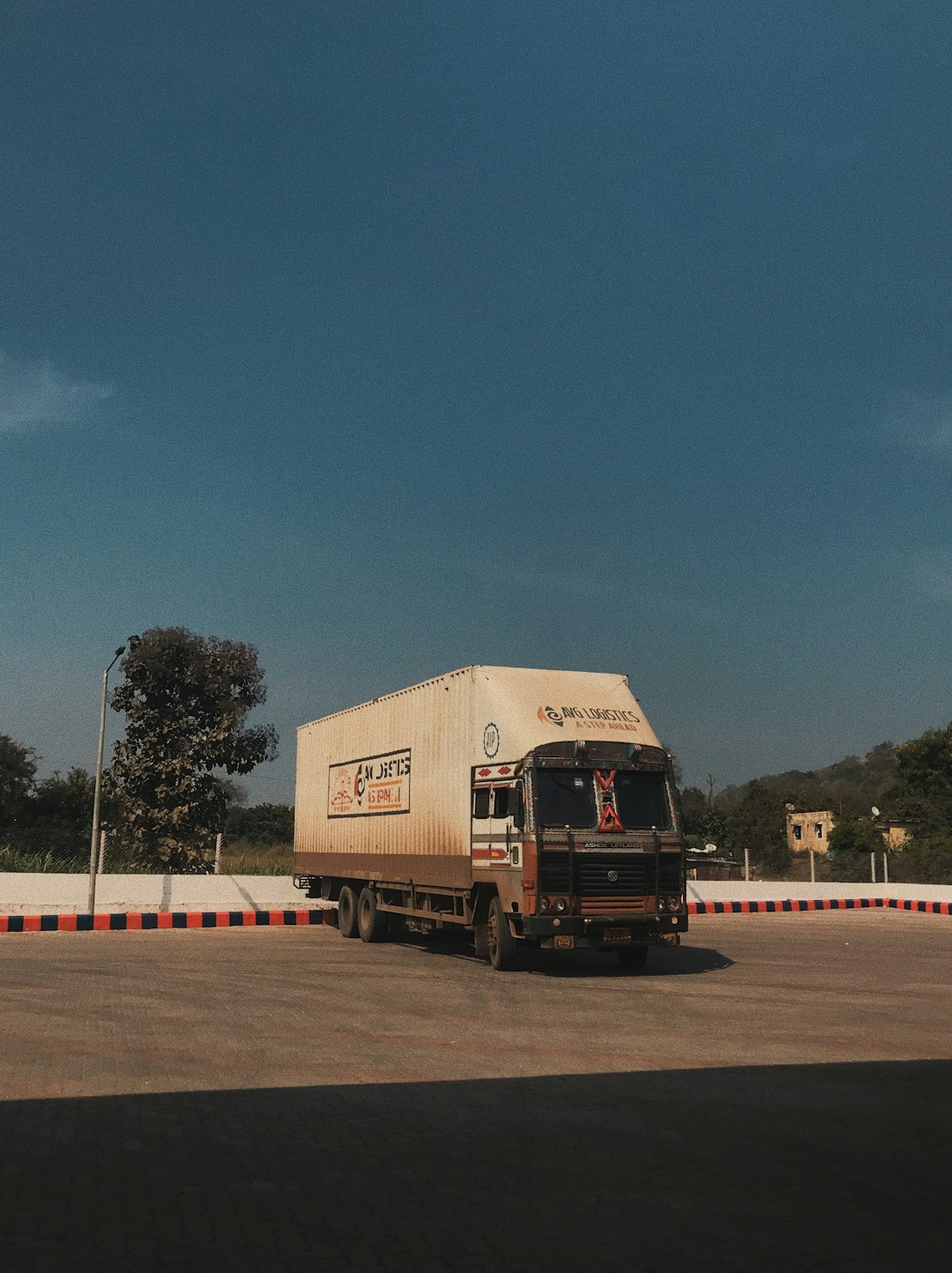 a large truck driving down a road under a blue sky indian roads, factory logistics, transportation issues
