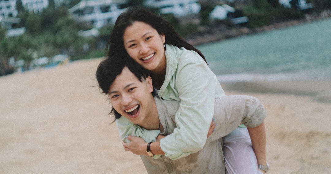 Couple laughing while enjoying a piggyback ride on beach grace chang david chang family hugo couple