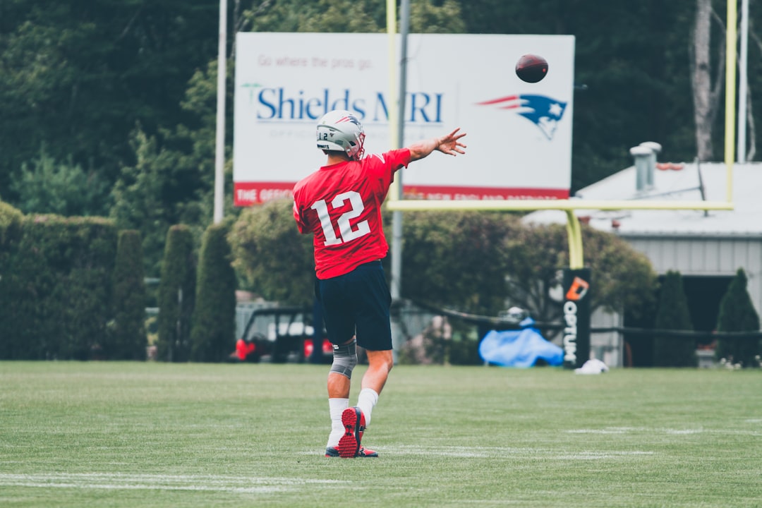 man in red and white football jersey holding white and red football tom brady, patriots, super bowl win