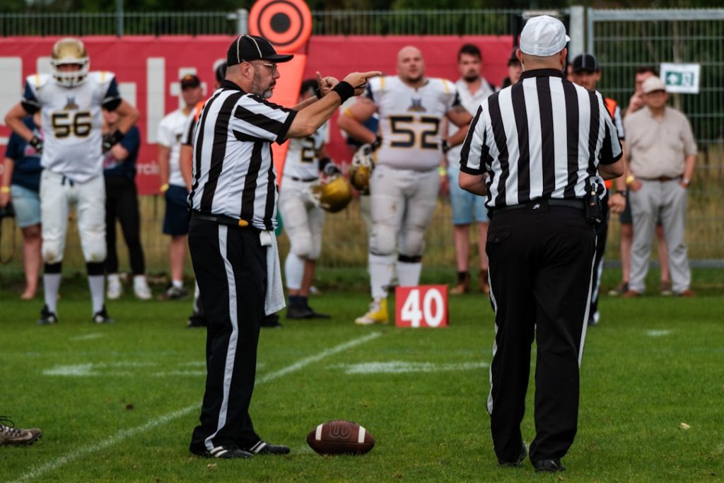 Referees on a football field with players in background. bills quarterback josh allen action