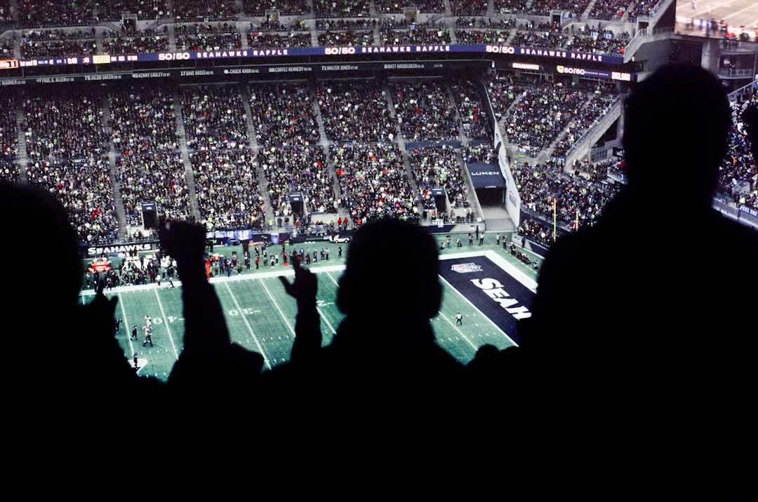 a crowd of people watching a football game football field scoreboard night game, dramatic fourth quarter, nfl fans cheering